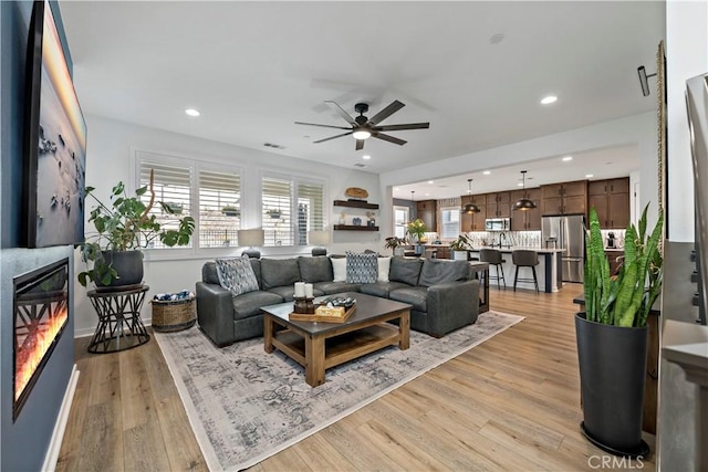 living room featuring ceiling fan and light hardwood / wood-style flooring