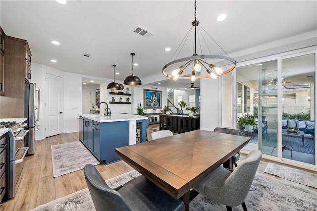 dining area featuring ceiling fan with notable chandelier, light hardwood / wood-style flooring, and sink