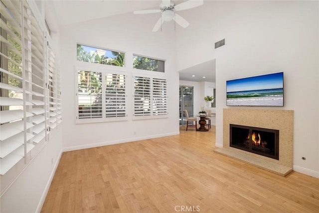 unfurnished living room featuring a premium fireplace, high vaulted ceiling, light hardwood / wood-style floors, and ceiling fan