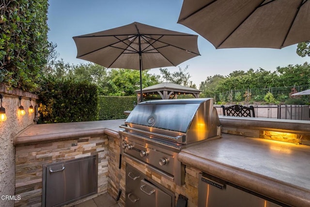 patio terrace at dusk featuring a grill and area for grilling