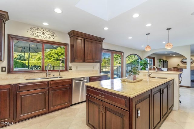 kitchen with stainless steel dishwasher, a kitchen island with sink, sink, and hanging light fixtures