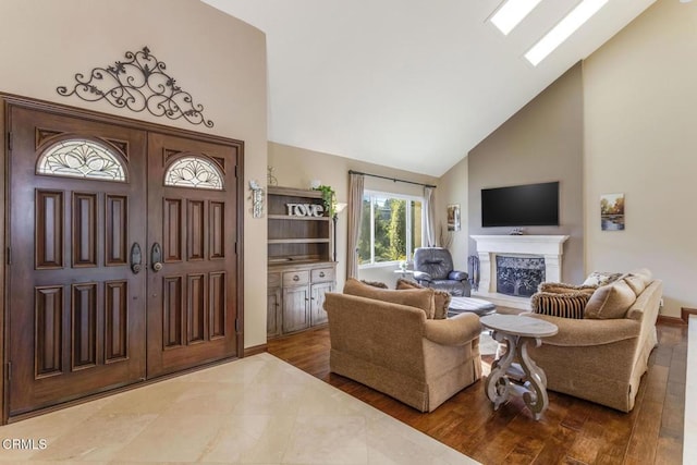 living room with hardwood / wood-style floors, a high end fireplace, high vaulted ceiling, and a skylight