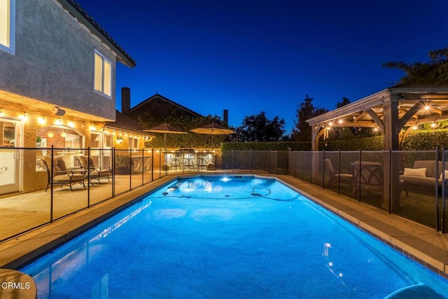 pool at twilight featuring a gazebo and a patio