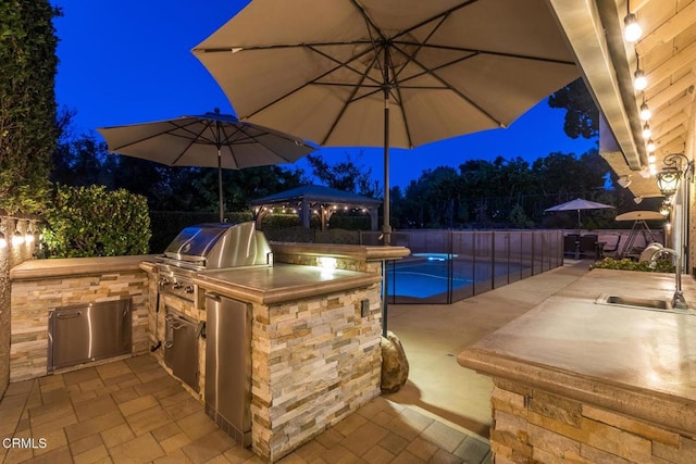 patio at twilight with a gazebo, area for grilling, and sink