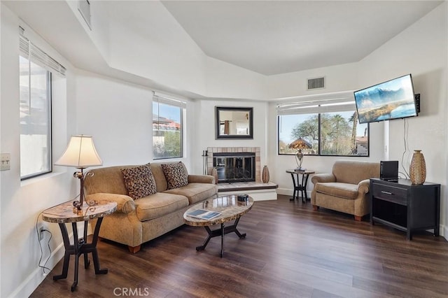 living room with dark wood-type flooring, a wealth of natural light, and a tile fireplace