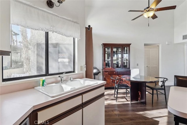 kitchen with a high ceiling, ceiling fan, dark hardwood / wood-style floors, and sink