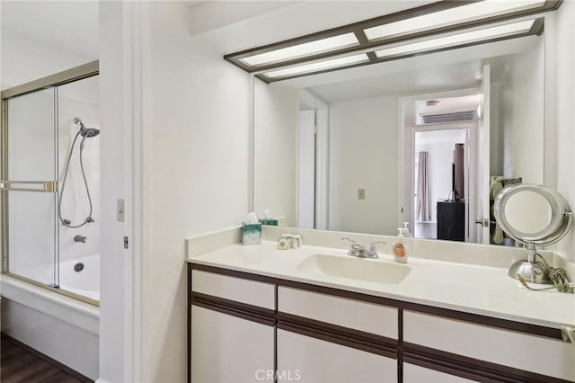 bathroom with combined bath / shower with glass door, hardwood / wood-style floors, and vanity