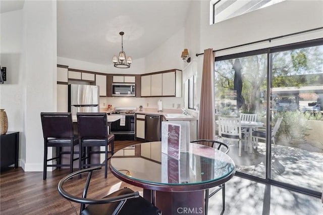 dining room featuring high vaulted ceiling, sink, dark hardwood / wood-style flooring, and a notable chandelier