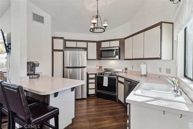 kitchen featuring decorative light fixtures, vaulted ceiling, an inviting chandelier, white cabinetry, and stainless steel appliances