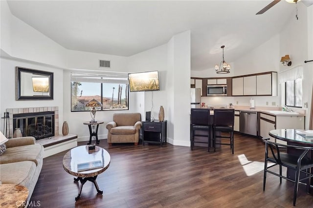 living room with ceiling fan, dark wood-type flooring, lofted ceiling, a tile fireplace, and sink