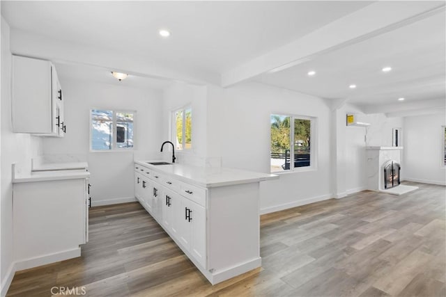 kitchen with white cabinets, kitchen peninsula, a healthy amount of sunlight, and sink