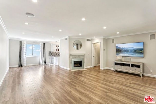 unfurnished living room featuring ornamental molding and light wood-type flooring