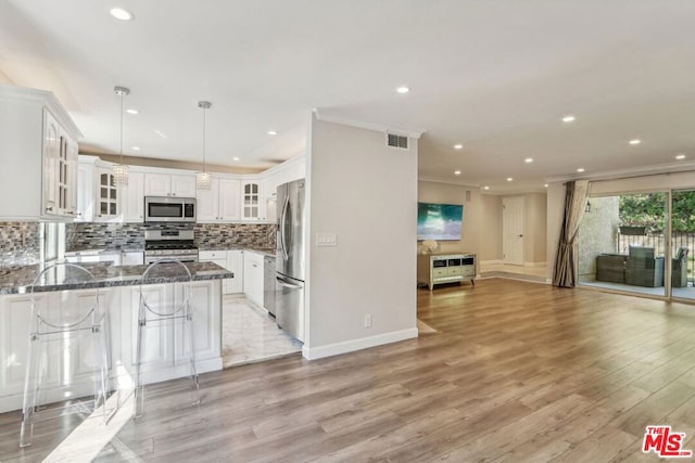 kitchen featuring light wood-type flooring, kitchen peninsula, stainless steel appliances, and dark stone counters