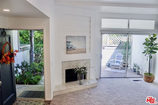 living room featuring plenty of natural light, carpet floors, and a tiled fireplace