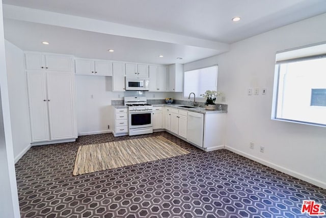 kitchen featuring white cabinetry, sink, dark carpet, and white appliances