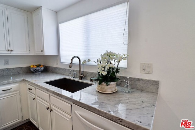 kitchen with white cabinets, dishwasher, light stone counters, and sink