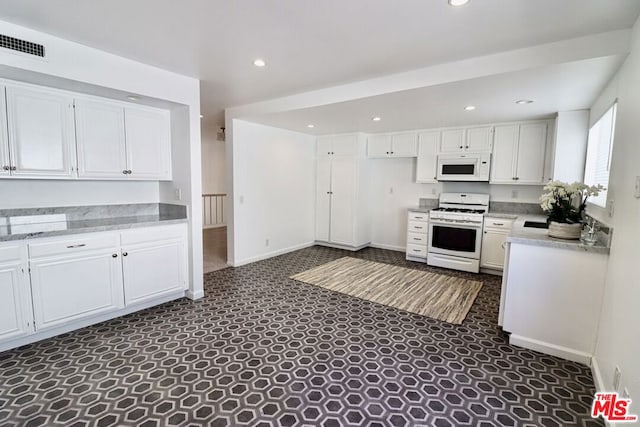 kitchen featuring white cabinetry, dark carpet, and white appliances