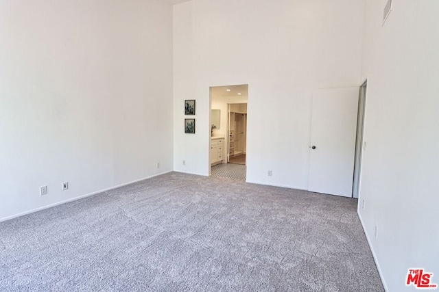 unfurnished room with light carpet and a high ceiling