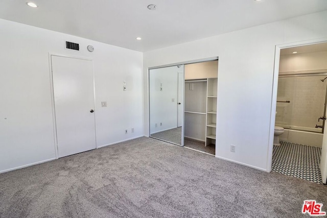 unfurnished bedroom with carpet flooring, ensuite bathroom, and a closet