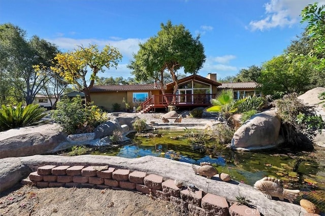 exterior space with a wooden deck and a small pond