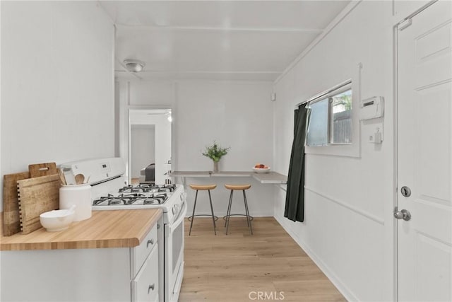 kitchen featuring butcher block countertops, white gas stove, light hardwood / wood-style floors, and ceiling fan