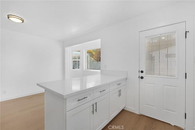 kitchen featuring kitchen peninsula, light wood-type flooring, and white cabinetry