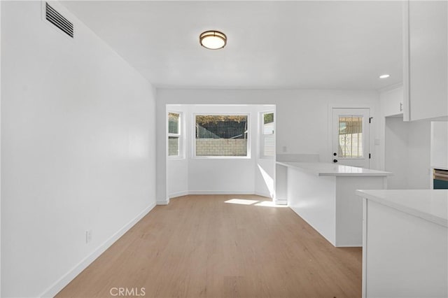 interior space featuring light hardwood / wood-style floors, white cabinetry, and kitchen peninsula