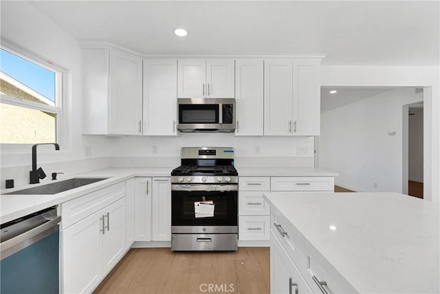 kitchen with sink, white cabinetry, stainless steel appliances, and light wood-type flooring