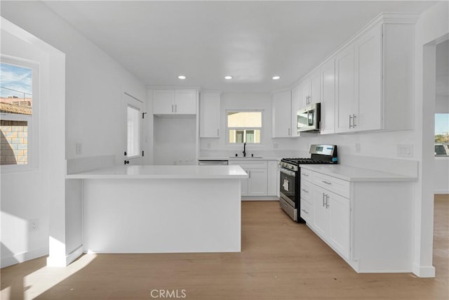 kitchen featuring a healthy amount of sunlight, white cabinetry, stainless steel appliances, and light hardwood / wood-style floors