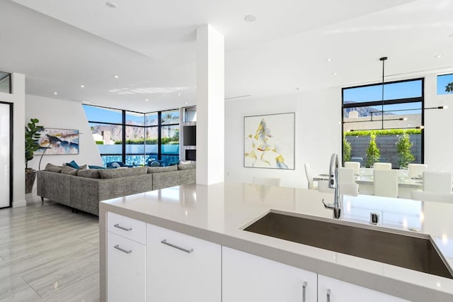 kitchen featuring white cabinetry, sink, floor to ceiling windows, and hanging light fixtures