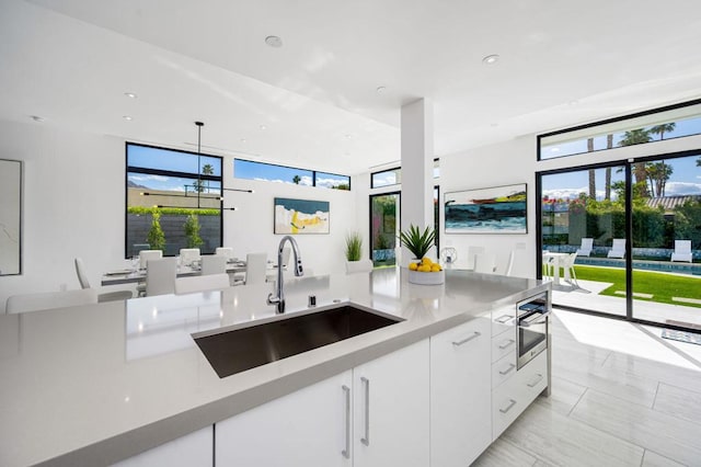 kitchen featuring white cabinetry, sink, and pendant lighting