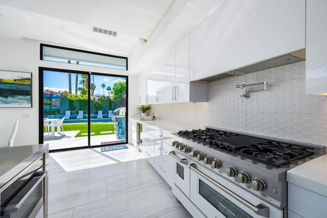 kitchen featuring range with two ovens, white cabinets, and decorative backsplash