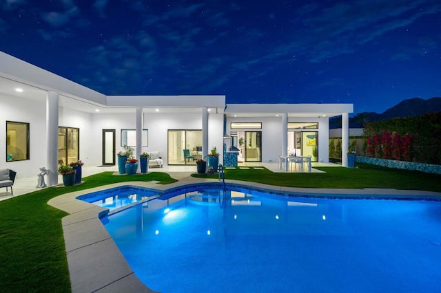 pool at night featuring a yard and a patio area