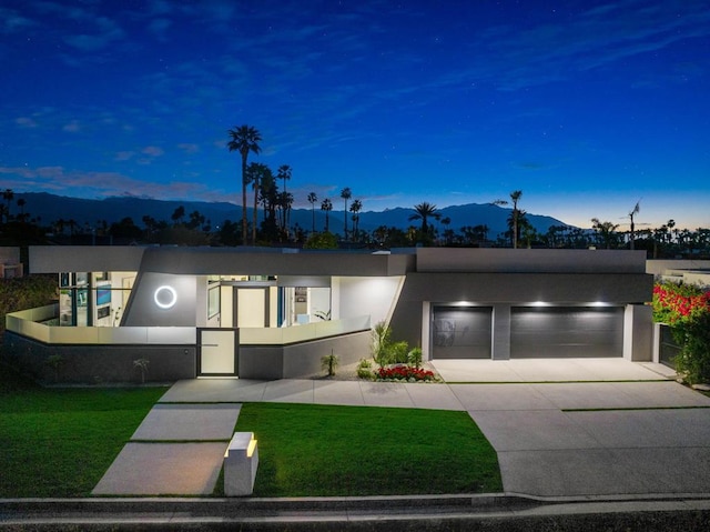 view of front of home featuring a garage, a mountain view, and a lawn