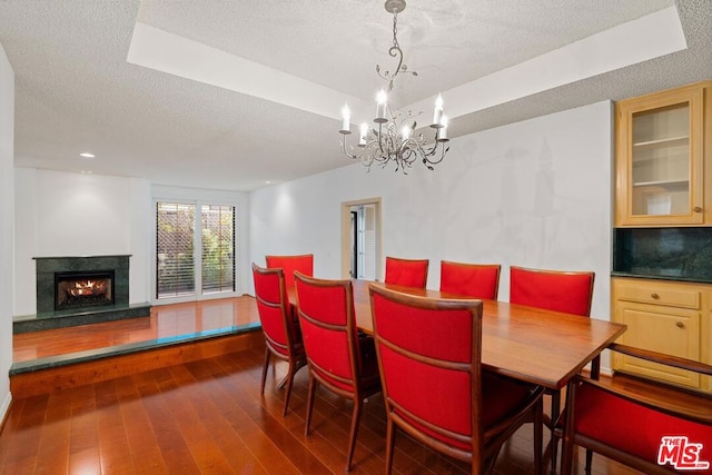 dining space featuring a textured ceiling, dark wood-type flooring, and a chandelier