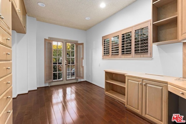 interior space with a textured ceiling, dark wood-type flooring, and french doors