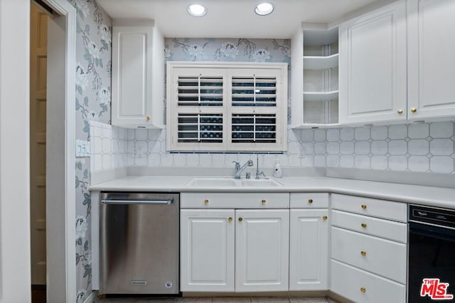 kitchen with stainless steel dishwasher, white cabinetry, sink, and tasteful backsplash