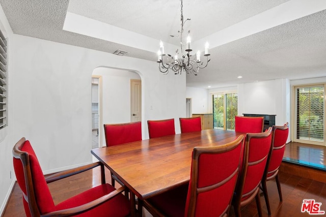 dining area with a chandelier, a textured ceiling, and dark wood-type flooring