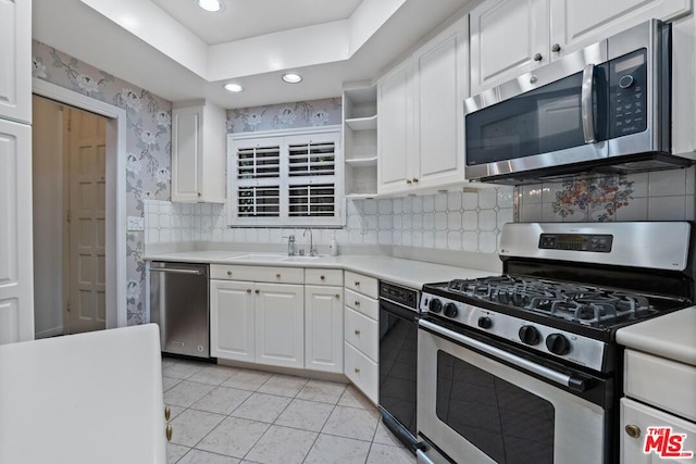 kitchen featuring white cabinetry, sink, stainless steel appliances, decorative backsplash, and light tile patterned floors