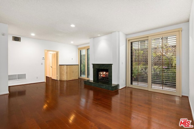 unfurnished living room with a fireplace, dark wood-type flooring, and a textured ceiling