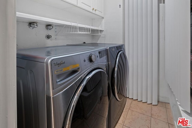 laundry area featuring light tile patterned flooring, cabinets, and separate washer and dryer