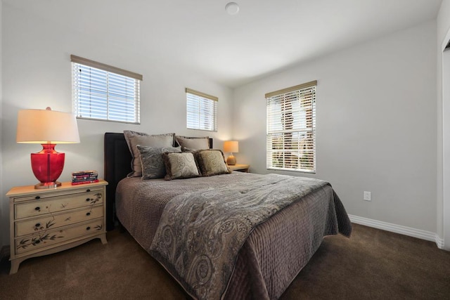 bedroom with dark colored carpet and multiple windows