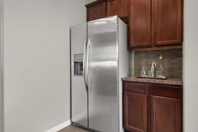 kitchen with stainless steel refrigerator with ice dispenser, dark stone countertops, and tasteful backsplash