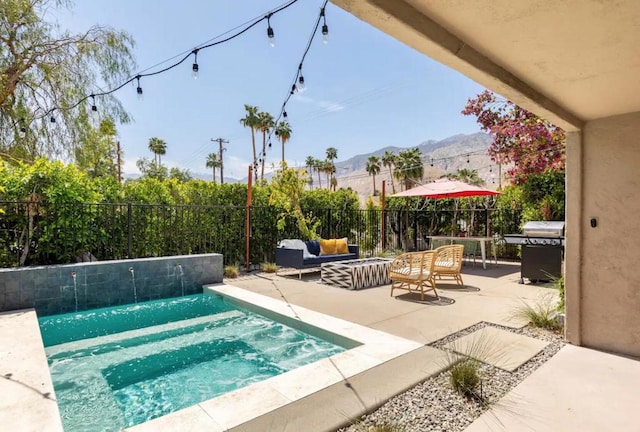 view of pool with outdoor lounge area, a grill, a mountain view, pool water feature, and a patio