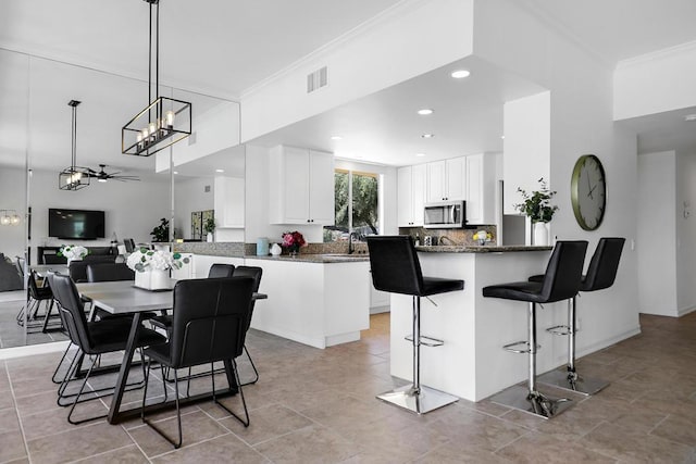 dining space with ceiling fan and crown molding