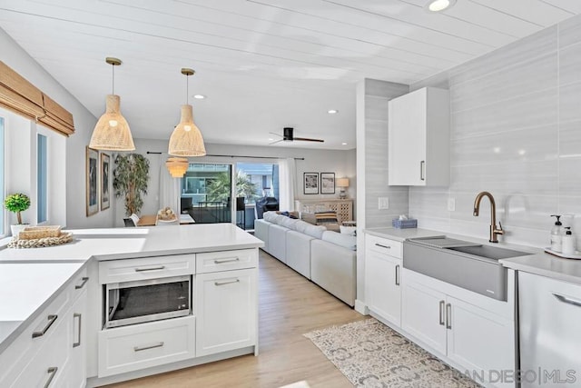 kitchen featuring white cabinets, pendant lighting, stainless steel microwave, and sink