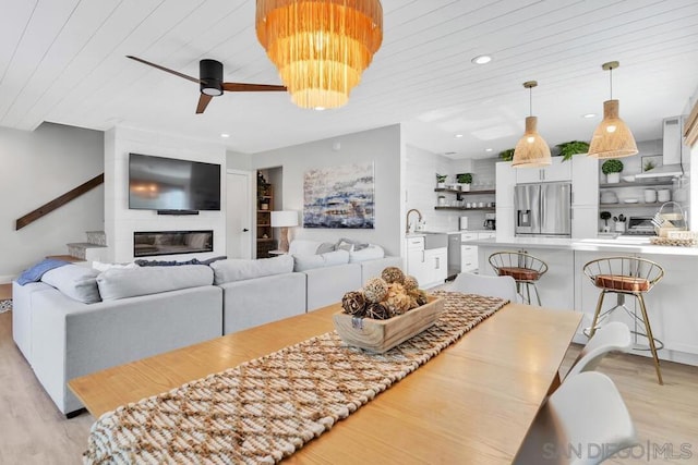 dining room with a fireplace, ceiling fan with notable chandelier, light hardwood / wood-style flooring, and wooden ceiling