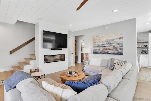 living room with ceiling fan, a fireplace, and light wood-type flooring