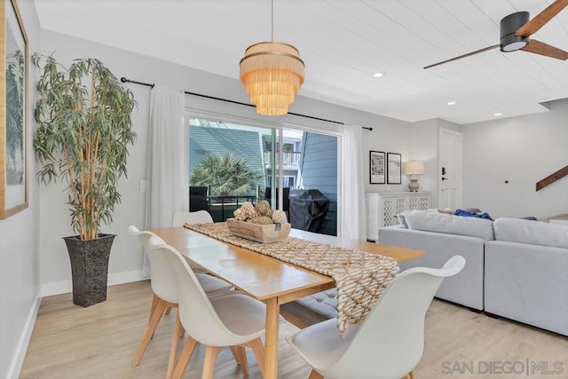 dining room with ceiling fan with notable chandelier and light wood-type flooring