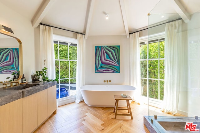 bathroom featuring lofted ceiling with beams, vanity, parquet flooring, and a washtub